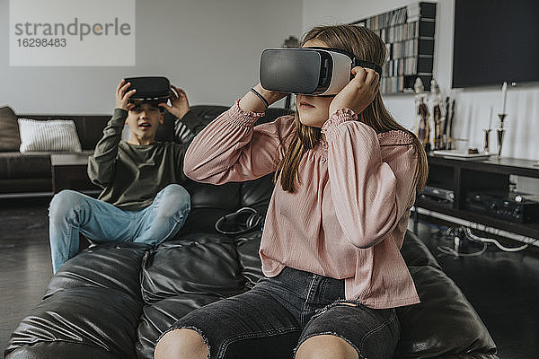 Freunde  die zu Hause auf der Couch sitzen und durch Virtual-Reality-Simulatoren schauen