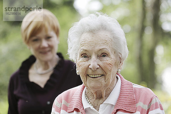 Deutschland  Nordrhein-Westfalen  Köln  Porträt einer lächelnden Seniorin mit einer reifen Frau im Hintergrund