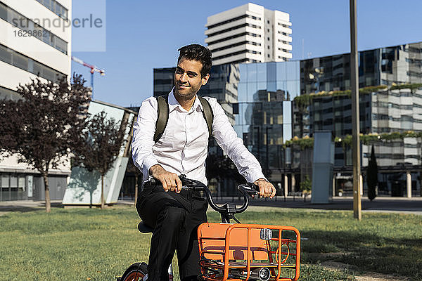 Männlicher Pendler fährt mit einem Elektrofahrrad gegen Gebäude in der Stadt