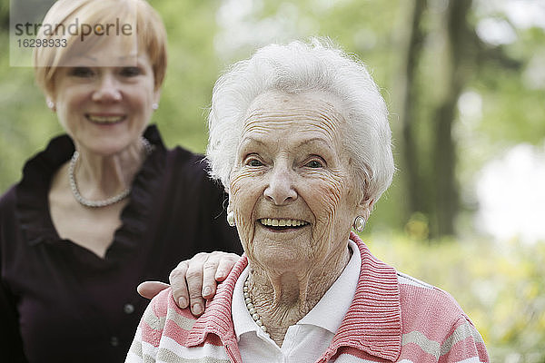 Deutschland  Nordrhein-Westfalen  Köln  Porträt einer lächelnden Seniorin mit einer reifen Frau im Hintergrund