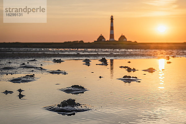 Deutschland  Schleswig-Holstein  Westerhever  Küstenpfütze bei Sonnenaufgang mit Leuchtturm Westerheversand im Hintergrund