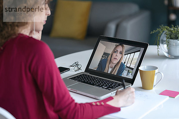 Junge Unternehmerin nimmt an einer Videokonferenz über einen Laptop im Home Office teil
