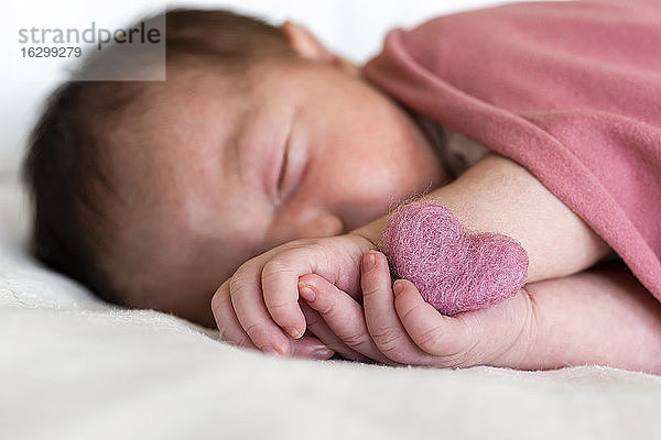 Nahaufnahme eines neugeborenen Mädchens mit Herzform  das auf einem Bett im Krankenhaus schläft