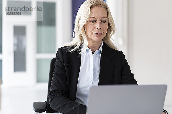 Selbstbewusste Geschäftsfrau  die zu Hause sitzend am Laptop arbeitet