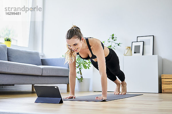 Frau lernt zu Hause mit Hilfe eines digitalen Tablets Übungen im Internet