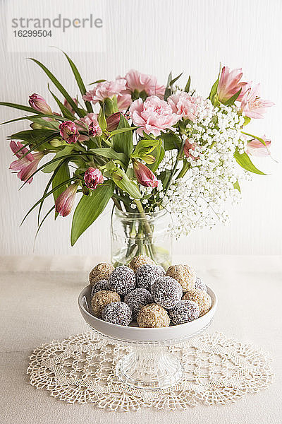 Glas mit rosa blühenden Blumen und Schale mit Eiweißbällchen