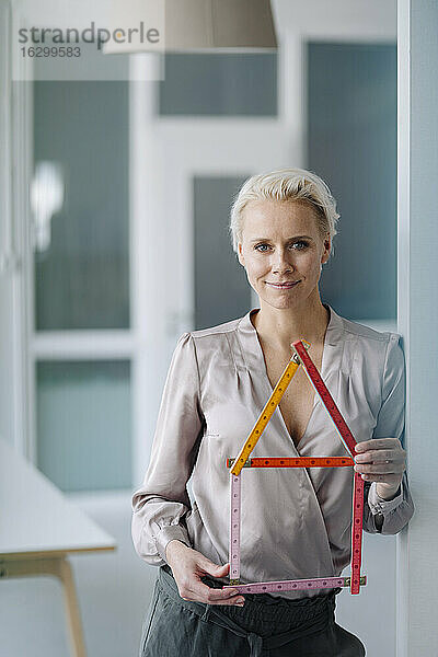 Selbstbewusste Architektin  die ein Modell hält  während sie im Büro steht