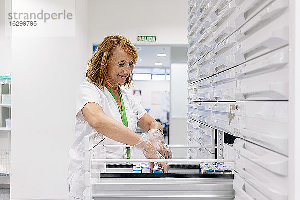 Lächelnde Pharmazeutin ordnet Medikamente in Schubladen im Labor