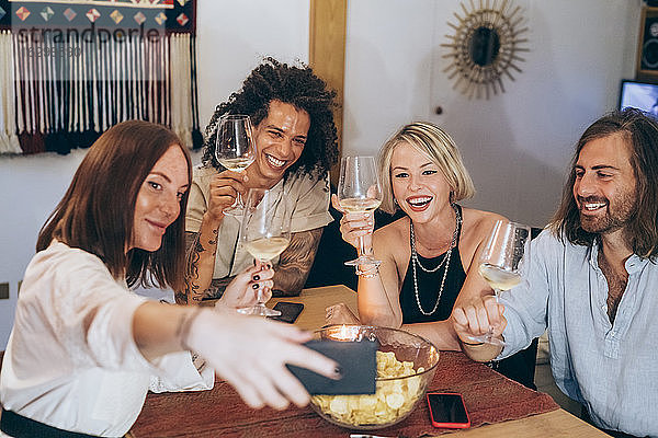 Frau nimmt Selfie mit fröhlichen Freunden genießen Wein während der Party