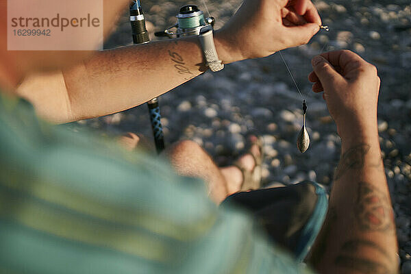 Nahaufnahme eines erwachsenen Mannes  der am Strand einen Fischzug vorbereitet