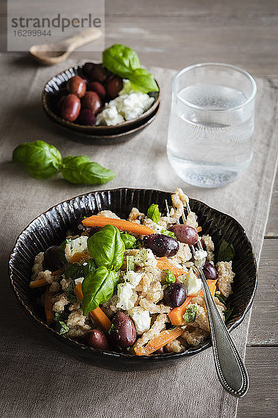 Schüssel mit vegetarischen Spätzle mit Karotten  Oliven  Fetakäse und Basilikum