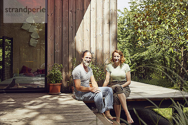Lächelndes Paar  das sich vor einem kleinen Haus entspannt