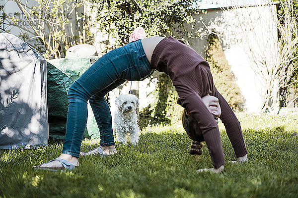 Mädchen beim Balancieren über Gras mit Hund im Garten