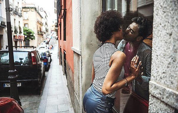 Romantisches Paar  das sich durch das Fenster eines Restaurants küsst