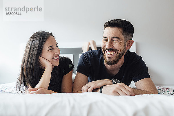Romantisches lächelndes Paar  das im Schlafzimmer zu Hause auf der Vorderseite liegt