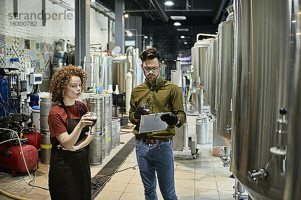 Ein Mann und eine Frau arbeiten in einer handwerklichen Brauerei und diskutieren über die Qualität eines Bieres