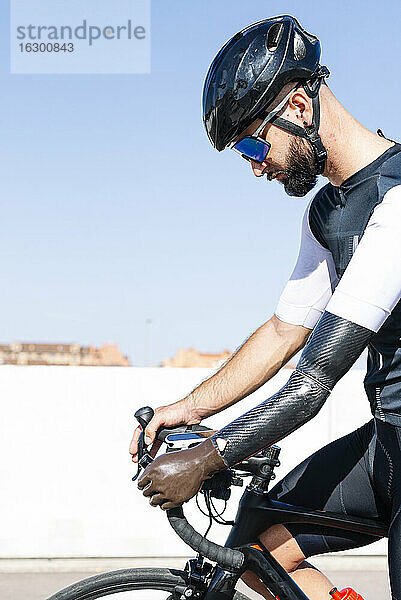 Männlicher amputierter Sportler fährt Fahrrad gegen den klaren Himmel an einem sonnigen Tag