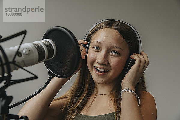 Nahaufnahme eines glücklichen Teenagers  der in einem Aufnahmestudio an der Wand singt