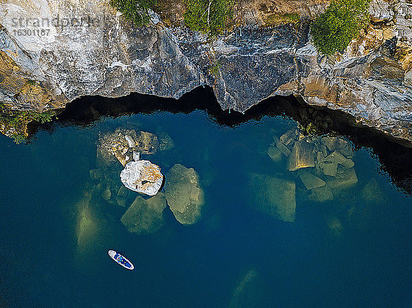Luftaufnahme eines Paddelboarders  der über im Marble Lake versunkene Marmorblöcke surft