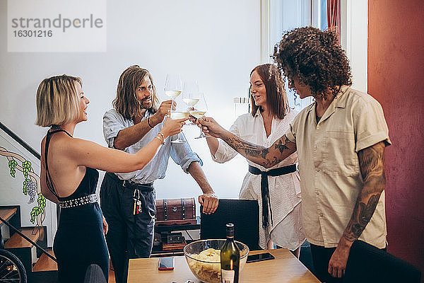 Männliche und weibliche Freunde stoßen mit Weingläsern während einer Party zu Hause an