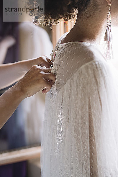 Frau Hand schließen Hochzeitskleid der Braut in der Umkleidekabine