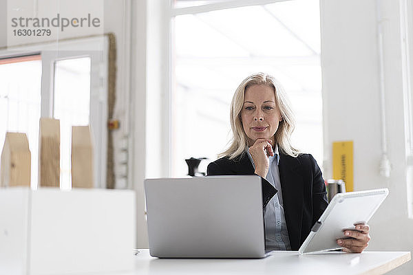 Unternehmerin mit Laptop und digitalem Tablet auf dem Schreibtisch im Heimbüro