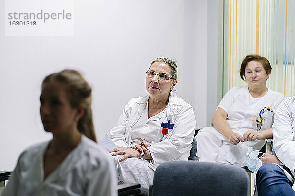Weibliche Ärzte hören zu  während sie in einer Besprechung im Krankenhaus sitzen