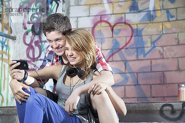 Deutschland  Berlin  Jugendliches Paar mit Handy  lächelnd