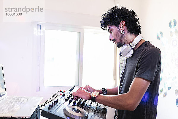 Junger männlicher Musiker  der in einem Aufnahmestudio als DJ den Ton mischt