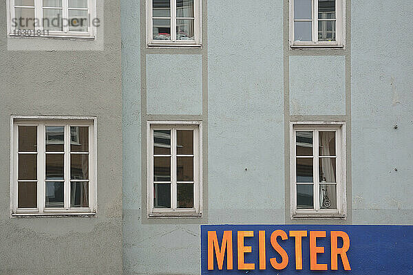 Deutschland  Bayern  München  Teil einer grauen Hausfassade mit Fenstern und Schild