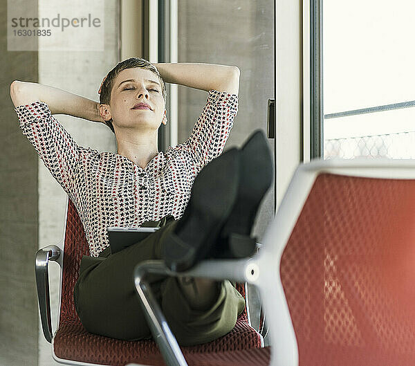 Entspannte Geschäftsfrau mit geschlossenen Augen  die auf einem Stuhl im Büro sitzt und eine Pause macht