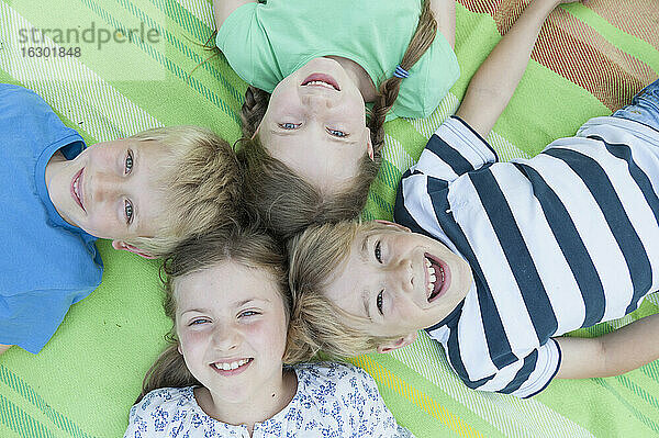 Deutschland  Bayern  vier lachende Kinder auf einer Decke liegend