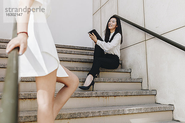 Geschäftsfrau steht neben einem lächelnden Mitarbeiter auf einer Treppe