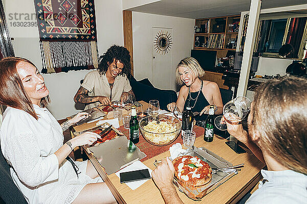 Fröhliche Freunde essen Pizza bei einer Party zu Hause