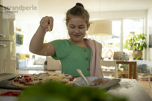 Nettes Mädchen bereitet Pizza mit Serviette über Kücheninsel