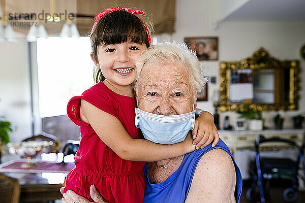 Großmutter und kleines Mädchen verbringen Zeit mit der Familie zu Hause  mit Gesichtsmaske