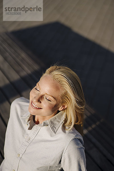 Lächelnde blonde Unternehmerin  die in der Stadt das Sonnenlicht genießt