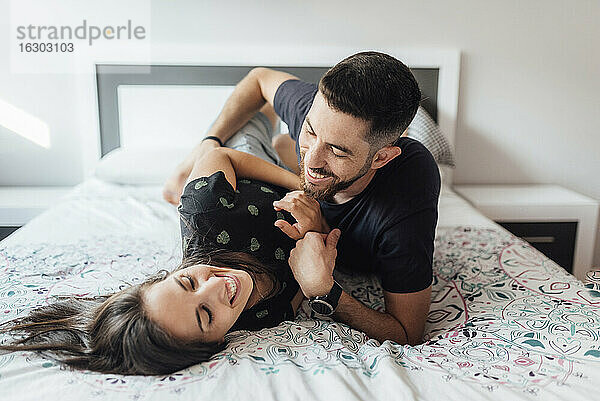 Lächelndes Paar spielt auf dem Bett im Schlafzimmer zu Hause