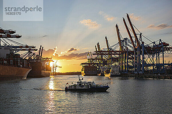 Deutschland  Hamburg  Motorboot fahren im Hamburger Hafen bei Sonnenuntergang