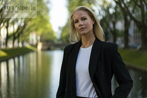 Schöne blonde Geschäftsfrau stehend gegen Kanal in der Stadt