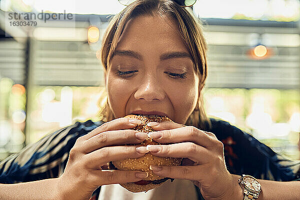 Porträt einer Frau beim Essen eines Burgers