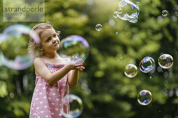 Nettes Mädchen schaut auf Blasen im Park