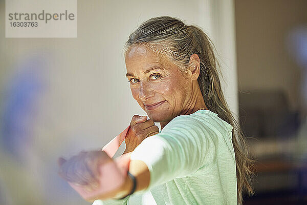 Lächelnde Frau  die mit einem Widerstandsband zu Hause trainiert