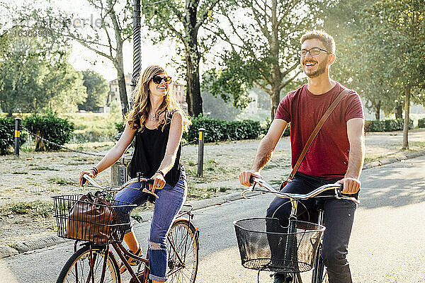 Glückliches Paar auf Fahrrädern auf der Straße im Park am Wochenende