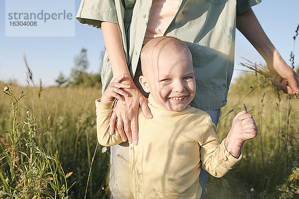 Glücklicher Junge steht mit seiner Mutter auf einem Feld an einem sonnigen Tag
