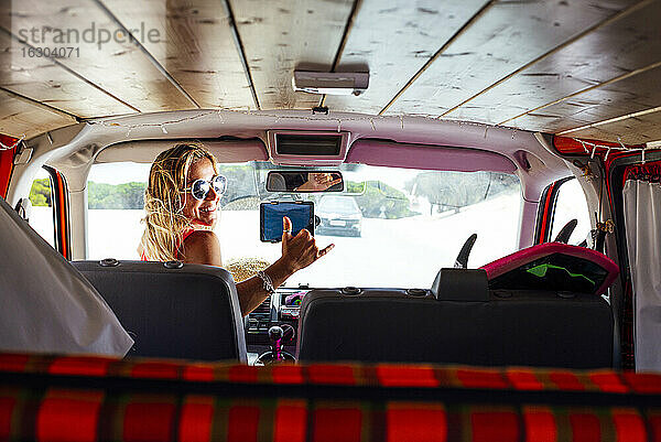 Lächelnde Frau  die in einem Van sitzt und über die Schulter schaut