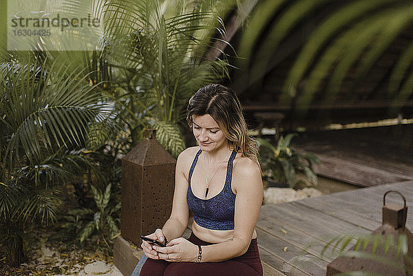 Lächelnde Frau mit Smartphone in einer Hütte