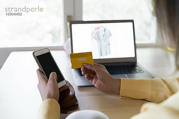 Junge Frau benutzt Kreditkarte und Smartphone für Online-Einkäufe zu Hause