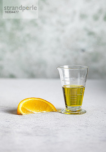 Eine Orangenscheibe und eine Tasse Olivenöl für die Vinaigrette