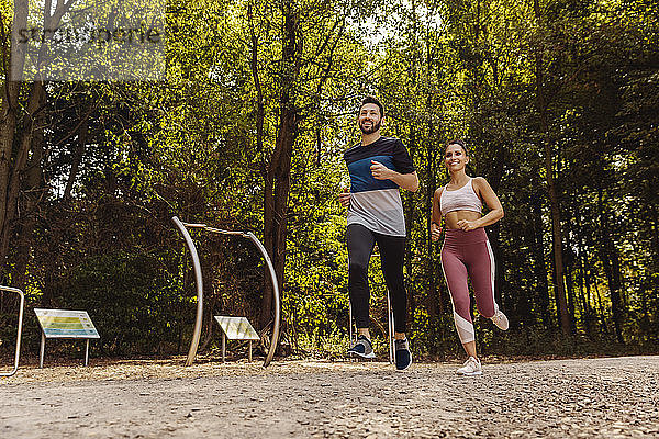 Sportlicher Mann und Frau laufen in der Nähe eines Fitnessparcours